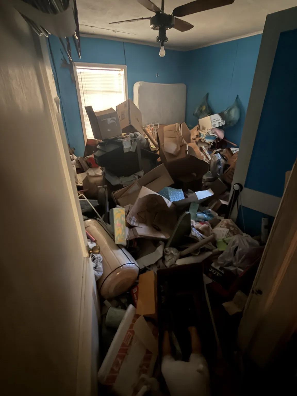 Bedroom containing furniture, boxes and loose items before cleanout