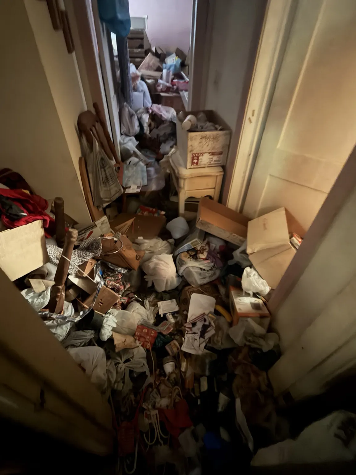 Narrow passage with household debris and belongings before cleanout