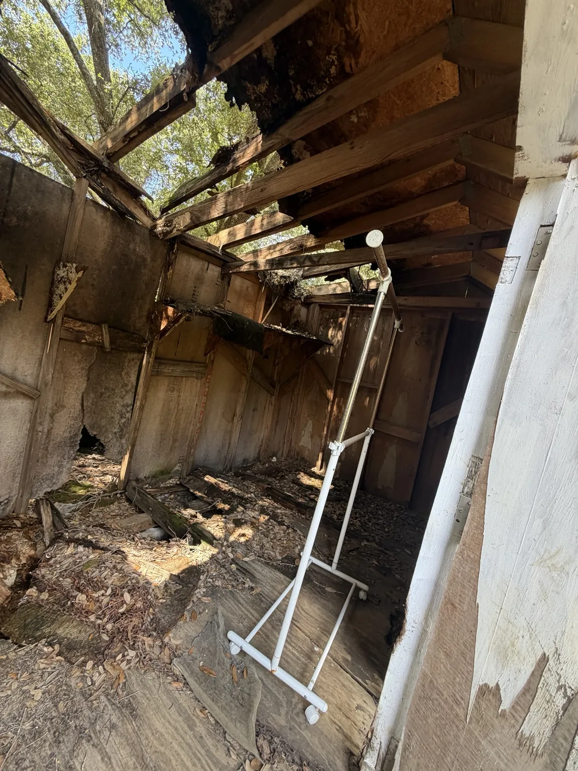 Inside the damaged shed with open roof sections and debris on the floor