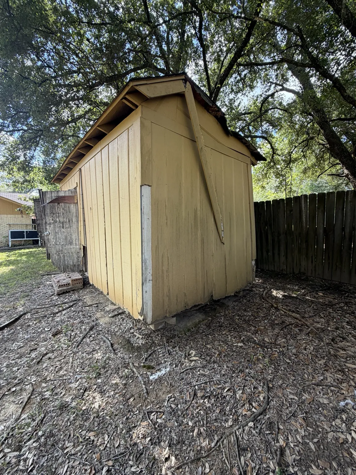 Side of the Frisco shed with weathered siding and roof damage