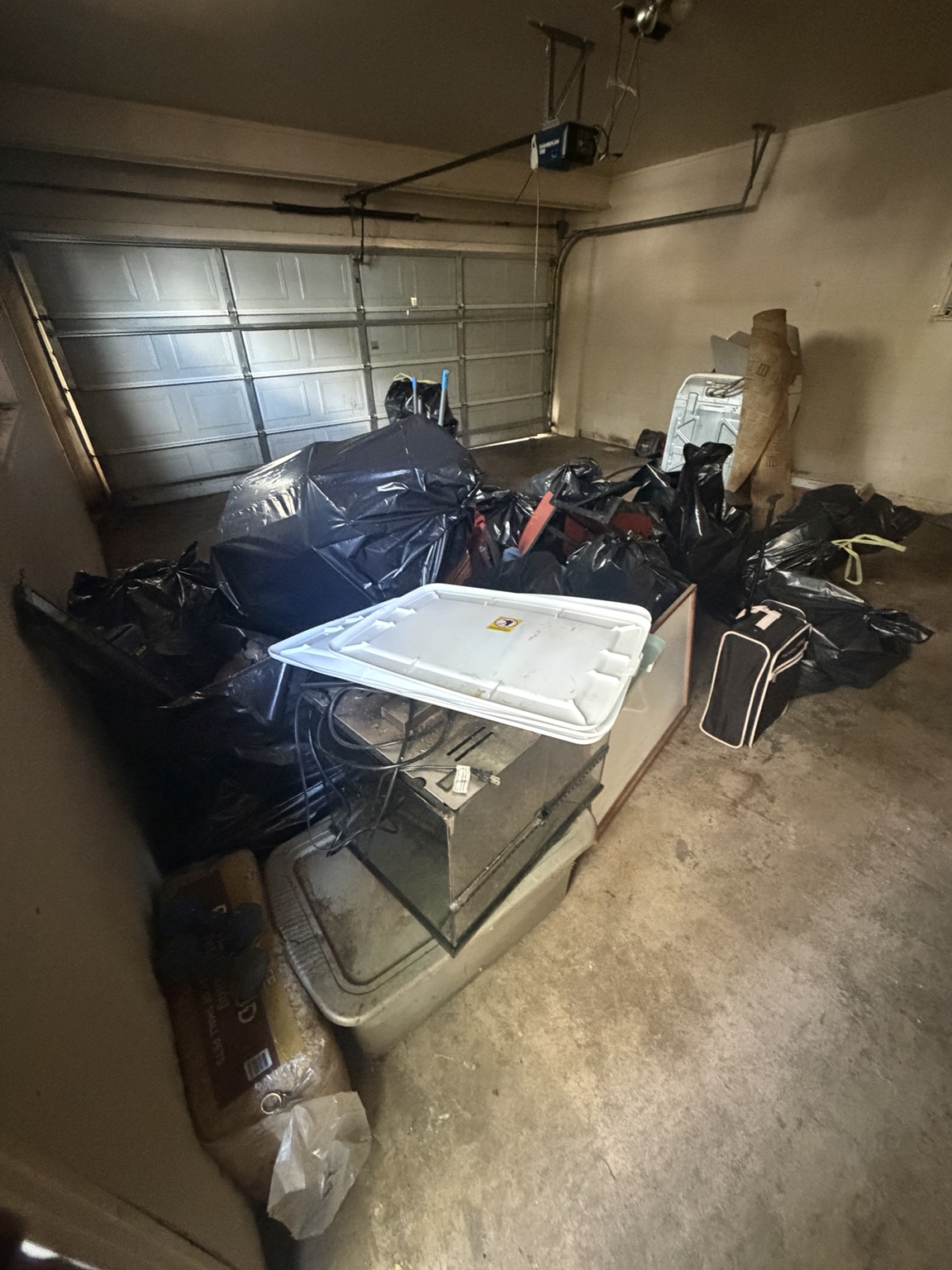 Bagged clutter and household items staged inside a garage