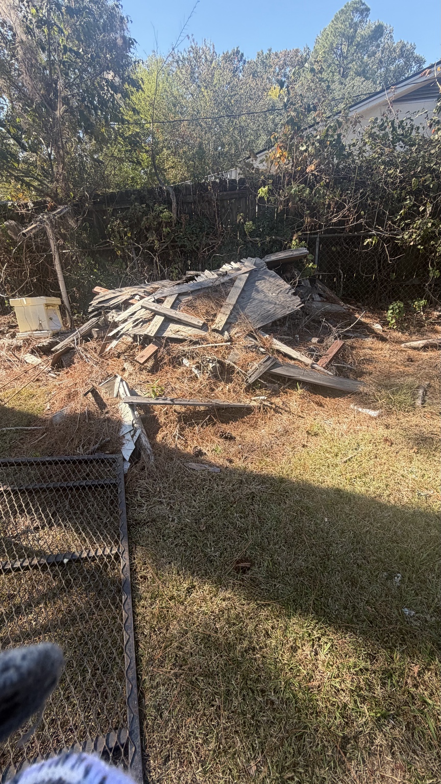 Wider view of the backyard debris pile at the property