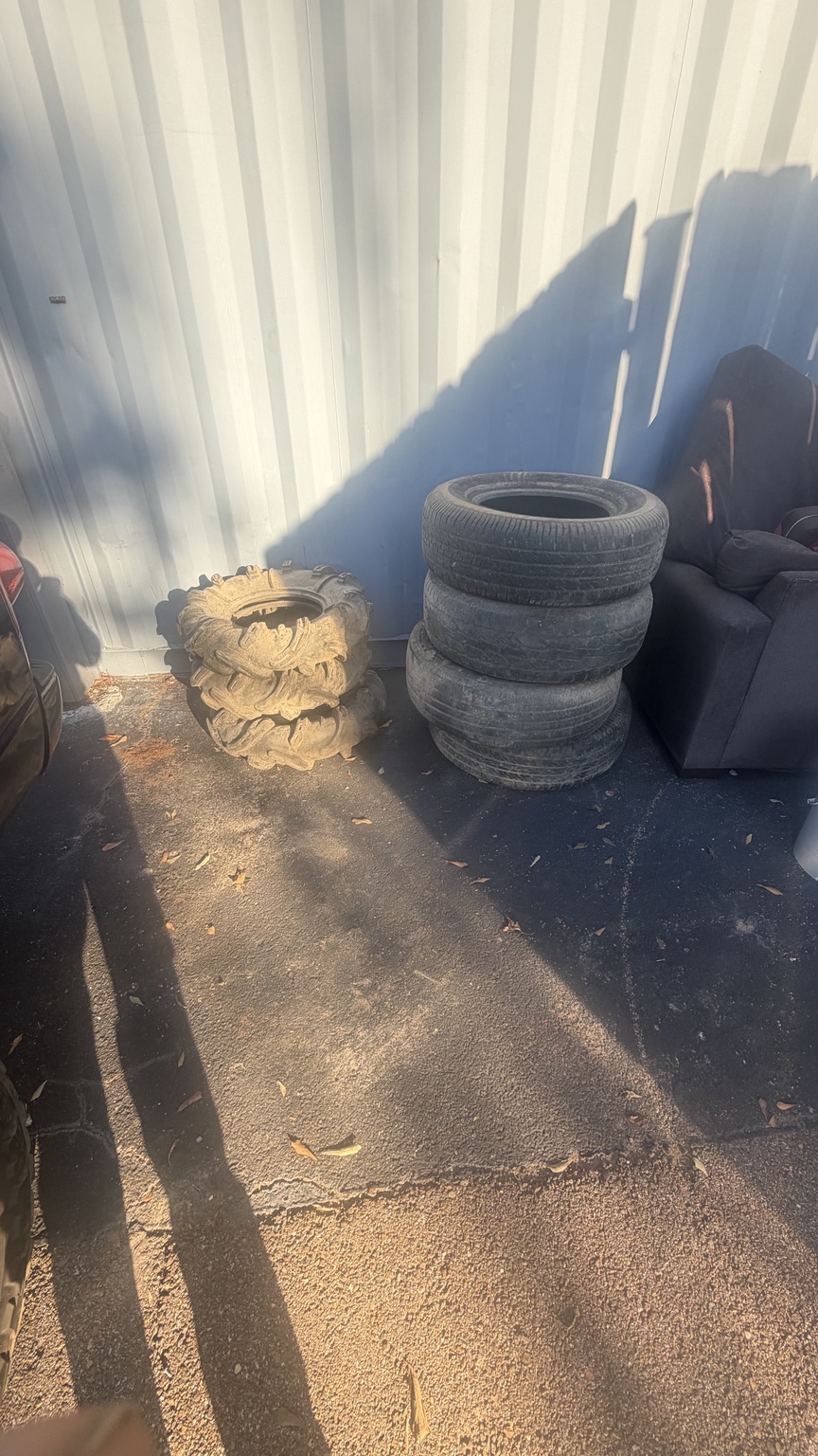 Tires stacked beside an exterior wall before pickup