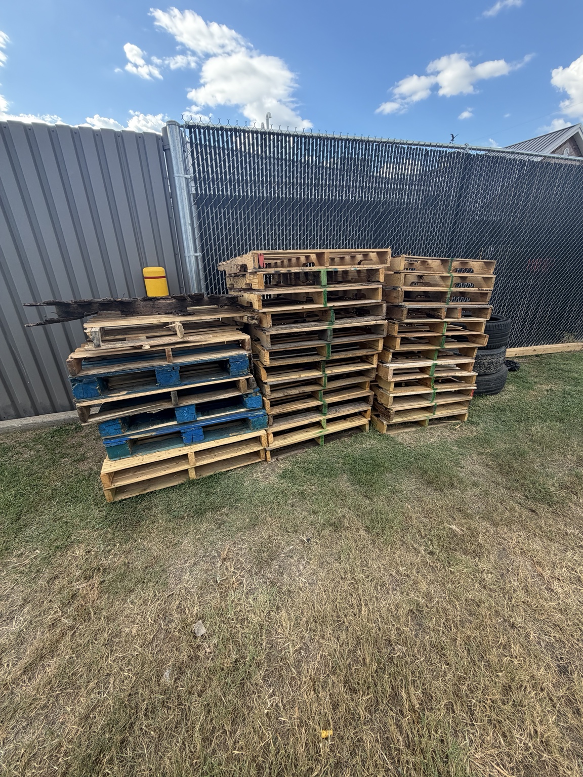 Stacked wooden pallets by a commercial fence