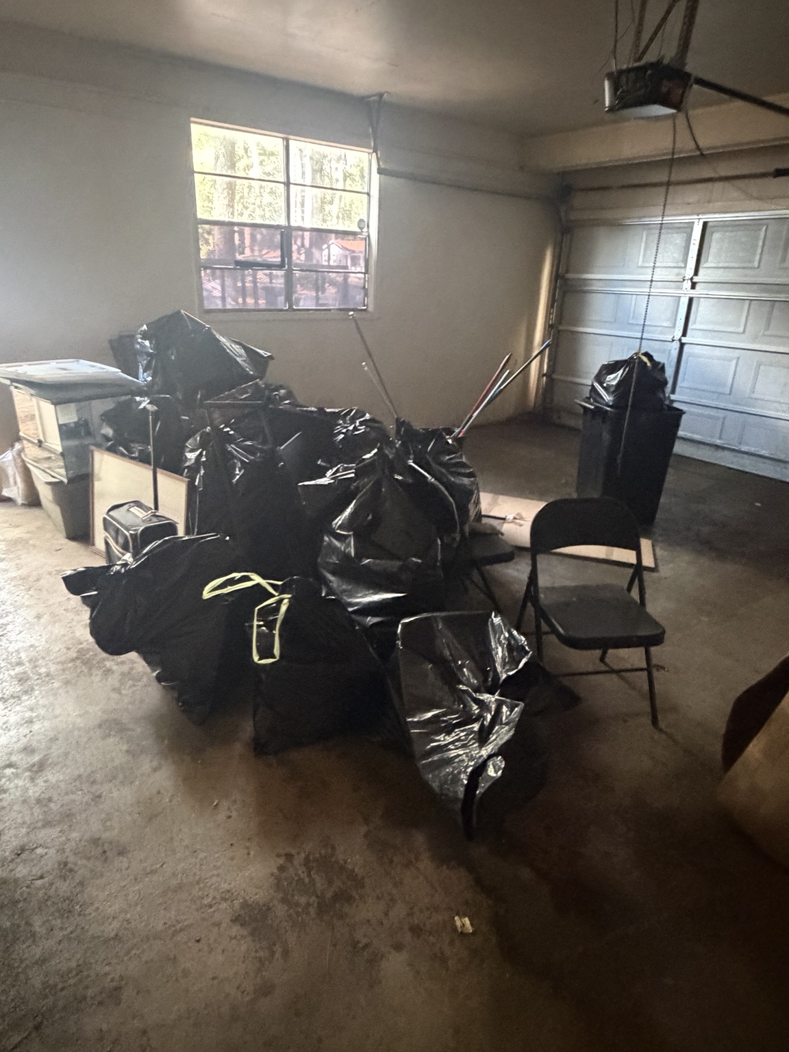 Bagged items and household clutter in a garage before cleanout