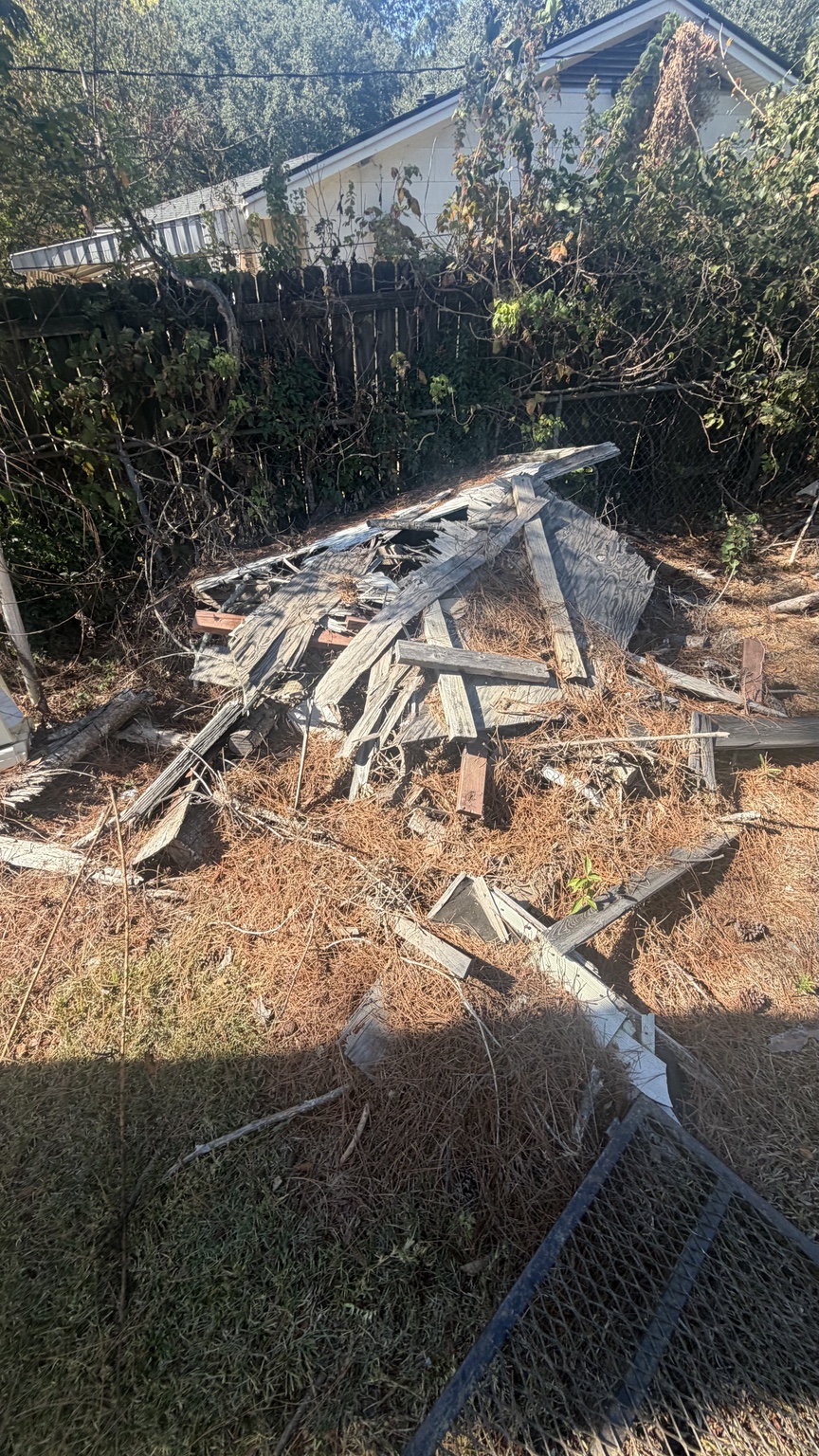 Weathered boards and debris in a backyard before removal